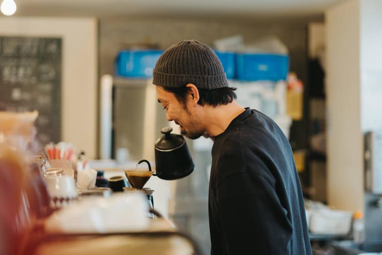 <span style="font-size:12px;"><font color="ffffff">姉の店から独立し、2010年にこのhazeを開業。屋号の「haze」とは、コーヒーを焙煎するときに豆がはじける「爆ぜる」に由来します。焙煎こそ、野尻さんのコーヒー人生における原点です。<br> <br> ぜひ飲んでほしいのは８種から選べるオリジナルブレンド。1〜8の数字は、メニュー入りした順のアーカイブになっています。最初に生まれたオリジナルブレンド「1」を飲むと、酸味が抑えられている一方で、苦味はやわらかく、コーヒーの旨みが口いっぱいに広がりました。<br> <br> 夜はゆっくりとした時間が流れているという野尻さん。<br> <br> 「この界隈はオフィス街なので、お昼どきは１分、１秒を争うくらいの忙しさですが、夜は仕事帰りの方が豆を買いに来がてら、ちょっとコーヒーを飲んでいく感じでしょうか。私自身もホッとひと息つける時間帯なので、一緒にくつろいでいってほしいですね」</font></span><br><br>