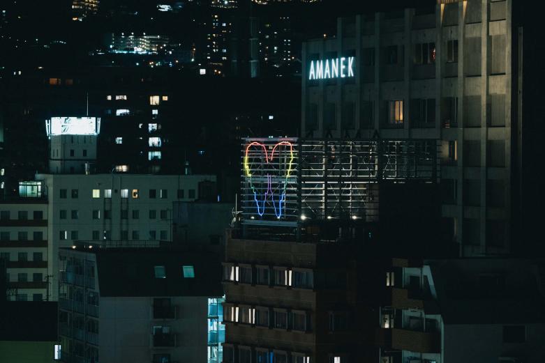 <span style="font-size:12px;"><font color="ffffff">別府駅にほど近いホテルの屋上に浮かび上がる、天使の羽。よく見ると七色の光がゆっくりと明滅を繰り返しています。<br> 実はこれ、トルコ出身でパリを拠点に活動する著名なアーティスト、サルキスの作品なのです。<br> <br>タイトルは『別府の天使』。天使はこれまでもたびたびサルキスの作品のモチーフとなっており、また、別府のまちを天使のように見守ってほしいという、このプロジェクトのディレクターの願いも込められています。ゆっくりと羽が現れては消えていくそのリズムは、サルキスの呼吸のリズムに合わせたものだそう。昼間は点灯せずにその姿を消し、夜になると現れる、夜しか出会えない作品なのです。 </font></span><br><br>