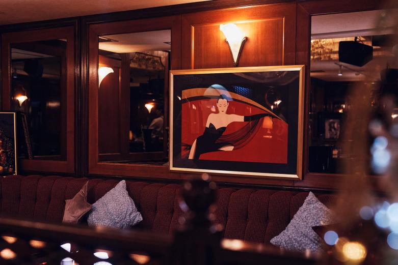 <span style="font-size:12px;"><font color="ffffff"> 壁にはノエビアのCMで一躍有名になった画家・鶴田一郎さんの美人画や、淳子ママが神と崇める荒井由実さんの写真も。気品あふれるクラシカルな雰囲気は、いつかの再放送で観た昭和ドラマのワンシーンのようで、うっとり。<br> <br> 「いまの時代、これほどの広さとレトロな造りを併せ持つクラブはなかなか珍しいかもしれませんね。スクラップ＆ビルドが繰り返される東京・銀座のような大都会の歓楽街では、古い店は大抵取り壊されるし、広い面積であるほど賃料も高くなりますからね……。都町だからこそ、創業時の面影をいまも色濃く残せているんです」（淳子ママ）</font></span><br><br>