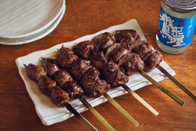 <span style="font-size:12px;"><font color="ffffff">写真右から「砂ズリ」250円、「鶏肝」塩・タレ 各250円、「鶏ハツ」250円。<br> <br> 「世間の物価高に負けず、従来のボリュームからできるだけ減らさないで、お安く提供しています。正直ちょっと苦しいけど……それでもお客さんの喜ぶ顔のために」と林田さん。<br> <br> 「鶏肝」はタレをチョイス。焼き場で何度もタレをつけているので、しっかり染みて美味。肉質がいいからクサミも少なく、塩で食べれば素材の旨さをより一層感じられます。<br> <br> 「鶏ハツ」（心臓）は開かずそのまま火を通してプリップリの食感を実現。「砂ズリ」は大きめのカットで独特の歯ごたえ。<br> <br> ふと、入口近くのショーケースに目が留まりました。なんと、日本各地から集めた約50種の地酒カップがズラリと並んでいるではありませんか。</font></span><br><br>