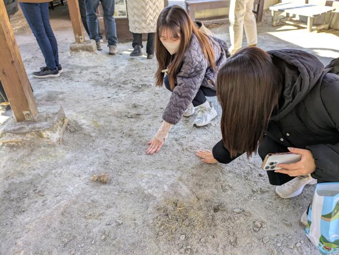 <span style="font-size:14px;">昔は300棟ほどあった「湯の花小屋」も、現在は15棟に減っているそうです。<br>湯の花を採取する職人の高齢化や「湯の花小屋」を建てる際に必要な藁が不足するなど、伝統を継承するには色々と課題もあるということでした。<br>私たちが説明を受けた場所にも、もともとは「湯の花小屋」が建っていたそうです。<br>実際に地面を触ってみるととても温かくて、この場所でも「湯の花」が製造されていたという歴史を感じました。</span><br><br>