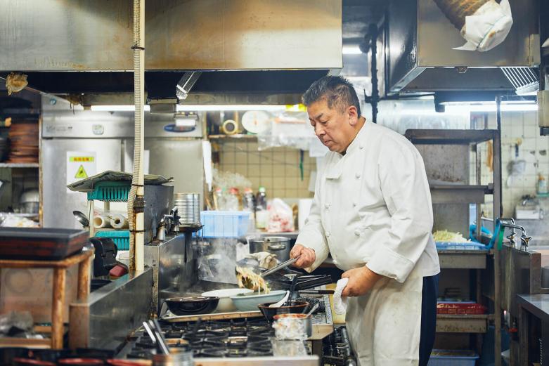 <span style="font-size:12px;"><font color="ffffff"> 料理長を務める3代目店主の佐々木美徳さん。東京銀座で中華の料理人として活躍した腕前で日々おいしい料理をつくり続けています。<br> <br> 寳屋オリジナルの日田チャンポンおいしさの秘訣は、野菜を炒めること。「通常は野菜を煮込むことが多いのですが、寳屋のチャンポンはあえて炒めています。炒めた野菜を麺の上からかけることでシャキシャキとした食感が残り、旨みが汁に溶け込んでおいしくなるんです。長崎チャンポンとはまた違って、いりこ出汁を使った醤油ベース。もともとうどん屋だったので、そのスープを先代がアレンジしてつくった代々伝わる秘伝の味です」と佐々木さん。</font></span><br><br>