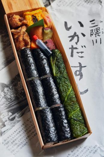 <span style="font-size:12px;"><font color="ffffff"> 〈ヤブクグリ〉の弁当第2弾として、2023年にリニューアルされた「三隈川いかだすし」1200円。<br> <br> かつて日田市で伐り出された木材は筏（いかだ）に組まれて筑後川を下り、有明海まで運ばれたことから筏に見立てた笹の容器を使用。三隈川のかっぱ伝説にちなみ、左には高菜、かんぴょう、きゅうりが入った「かっぱ巻き」、右には梅と長芋が入った酢飯を高菜漬けで巻いた日田発祥の郷土料理「高菜巻き」が。</font></span>