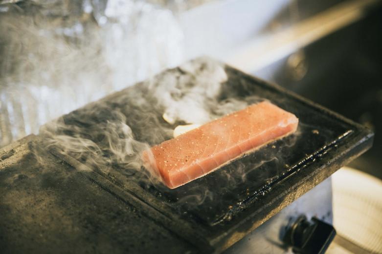 <span style="font-size:12px;"><font color="ffffff">そしてもう一品、ここの名物はライブ感あふれる「まぐろステーキ」。鹿児島県の溶岩を使った特注のプレートに乗ったマグロのサクと山盛りのもやしが、豪快な音と湯気と共に運ばれてきます。</font></span><br><br>