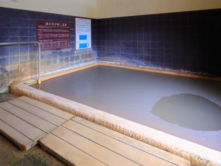 湯の花が表面に浮遊する内湯。底から注がれる新鮮な湯が特徴