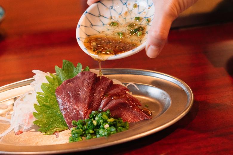 <span style="font-size:12px;">村上さんいわく、通な常連さんはシン刺し全体にごま塩ダレをかけてから生姜醤油につけて食べるそう。ごま油とすりごまの香りをたっぷりまとったシン刺しに、ちょんと生姜醤油を付けて食べれば、自然と笑みがこぼれてしまいます。<br><br> 一力のメニューはヒレ角切や、ロース、カルビ、ミノ、タン、ホルモンなどがランクに別に14種類。刺身はミノ刺し、シン刺し、生センマイの３種類。その他は野菜やスープ、キムチ、ご飯といたってシンプルです。<br><br> 100年の歴史がある大分県のブランド和牛・おおいた豊後牛（おおいた和牛）。大分県では多くの和牛農家さんが繁殖や肥育に長年力を注いできたからこそ、おいしい新鮮なお肉がこうやって身近で食べられるのですね。</span><br><br>