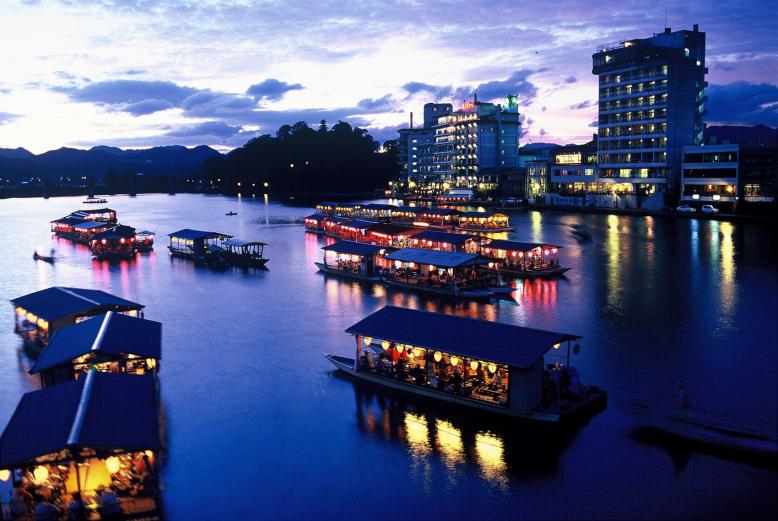 <span style="font-size:12px;">日田では屋形船は「遊船(ゆうせん)」とも呼ばれています。<br>江戸時代、代官たちは屋形船で贅沢なひとときを楽しんでいました。その伝統は今も日田の川辺で息づいています。三隈川に浮かぶ屋根付きの船に身をゆだねれば、川風に吹かれながらゆったりと食事を楽しむ時間が流れます。提灯の柔らかな灯りが船内を包み、川面に映る街の光と相まって、日常を忘れさせる幻想的なひとときに。歴史あるまちの夜を、現代でも気軽に味わえるのが、日田ならではの屋形船体験です。</span><br><br>