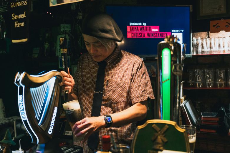 <span style="font-size:12px;">終始にこやかな笑顔でビールを注いでくれるマチオさん。物腰やわらかで飄々とした人柄ですが、これまで何千杯と注いできた技術とビール愛に裏打ちされた自信は本物です。<br> <br> 特にギネスは、「カスケードショー」と呼ばれる、グラスに注ぐと現れる細かい泡が下から上へ昇る現象が特徴ですが、泡の上昇時間はその日の室温などにも左右され、ビールの味わいにも影響を与えます。きめ細かな泡こそマイスターの証。実は繊細な技術が求められる熟練技なのです。</span><br><br>