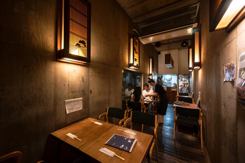 <span style="font-size:12px;">都町の路地にひっそり佇む『蕎麦Bar　齋』。外の喧騒を忘れさせるコンクリート打ちっぱなしの壁と、柔らかな木の欄間が織りなす静謐な空間は、まさに大人の隠れ家と呼ぶにふさわしい場所。やわらかな灯りがともる夜の時間にこそ、この店の魅力が際立ちます。<br> <br> 店内に足を踏み入れると、まず目を引くのはスタイリッシュながらもどこか温かみのある佇まい。青森産有機そばの中心部だけを使った白い蕎麦は、口に含むとしなやかに喉を滑り、淡く上品な香りが鼻腔をくすぐり、細打ちの蕎麦は、日本酒や季節の酒肴との相性もよく、ゆったりと流れる時間にそっと寄り添います。</span><br><br>