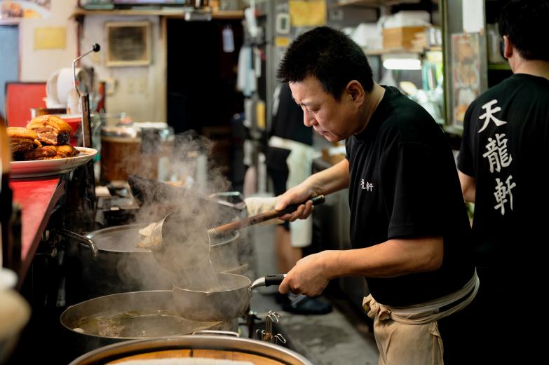 <span style="font-size:12px;">先代の味を受け継ぐ大将の池辺政人さん。<br> カウンターに座れば、常連と初めての客が肩を並べ、思わず笑顔になる温かい空間。<br>大将の「来てくれた人に笑顔になってもらいたい。お客さんがいるからこそ続けられている、感謝しかないですね」という言葉が、この店の味わいを一層深くしてくれます。</span><br><br>