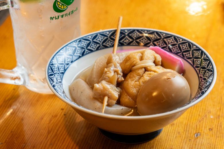 <span style="font-size:12px;"><font color="ffffff"> おでん各種150円〜500円。<br> <br> 最後に案内するのは、竹田の終着地と呼ばれる〈常連〉です。<br> <br> 堀場夫妻は、「常連をひと言でいうと、“家”！」というほど、アットホームなお店なのだとか。というのも店主の高嶋聖香さんは、３歳頃から竹田で育った生粋の竹田っこ。面倒見がよく祭り好き、地域のよき姉貴分として慕われているのです。<br> <br> そんな常連で、寒い冬にいただきたいのは熱々のおでん。聖香さんが入ってきたお客さんの顔をみて「なん食べる？」と温かい料理を勧めてくれるはずです。<br> <br> 竹田名産のかぼすのサワーに合わせて、大根、こんにゃく、玉子、牛すじ、餅巾着など定番のおでんの具を盛り合わせてもらいました。<br> <br> やさしい出汁が胃袋に染み渡る……！</font></span><br><br>