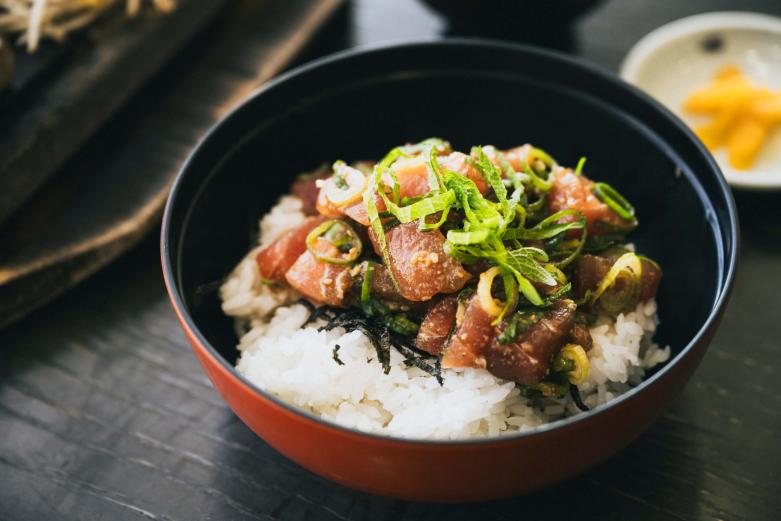 <span style="font-size:12px;"><font color="ffffff">保戸島で古くから伝わる漁師料理「ひゅうが丼」1300円（写真は小盛1050円）。地元では知らない人はいない定番の郷土料理です。<br> <br> 「保戸島の漁師が過酷な漁の合間に手早く栄養がとれるようにと考案された漁師飯です。名前の由来は、船上で突風が吹き“ひゅーひゅー”と音が聞こえていたことからこの名がついた、など諸説あります。<br> <br> マグロのぶつ切りを醤油や砂糖を合わせたタレに混ぜ込んで、炊きたてのご飯の上にのせて食べる豪快な漁師飯。過酷な遠洋漁業の疲れを癒すために、味つけは甘めです。香ばしいすり胡麻やねぎなどの薬味をのせ、仕上げに卵の黄身を加えて濃厚かつマイルドに仕上げるのが、うちのひゅうが丼の特徴ですね」と、浜茶屋の板長・簑部雅人さんが教えてくれます。</font></span><br><br>