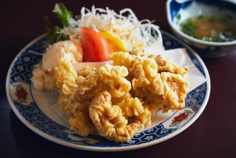 <span style="font-size:12px;"><font color="ffffff">大分といえば「とり天」700円。ムネ肉を使用する店が多いなか、〈寳屋〉ではモモ肉を使用することでやわらかくジューシーな仕上がりに。<br> <br> さらに、日田グルメとしてチェックしたいのが、〈日田きこりめし〉。画家・牧野伊三夫さんが発起人として立ち上がった、日田の林業応援団体〈ヤブクグリ〉から生まれたユニークな弁当です。江戸時代から林業が盛んな日田のシンボルともいえる日田杉は、JR日田駅の駅舎にも使用されているほど、深いつながりをもっています。日田杉を使った商品づくりや、森林への興味を促す活動を行っている〈ヤブクグリ〉の活動の一環として2013年２月に誕生。今や県外でも注目を集める弁当になったのですが、それを実際に製造・販売しているのが〈寳屋〉なのです。</font></span><br><br>